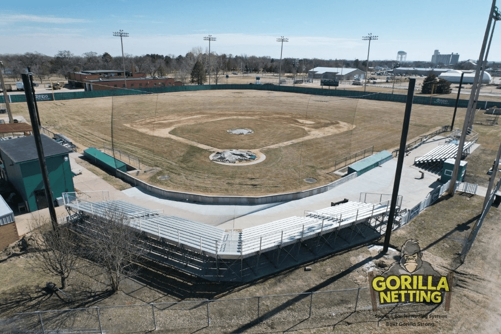 Elevated view of a baseball field showing cable-suspended backstop netting protecting spectator bleachers behind home plate