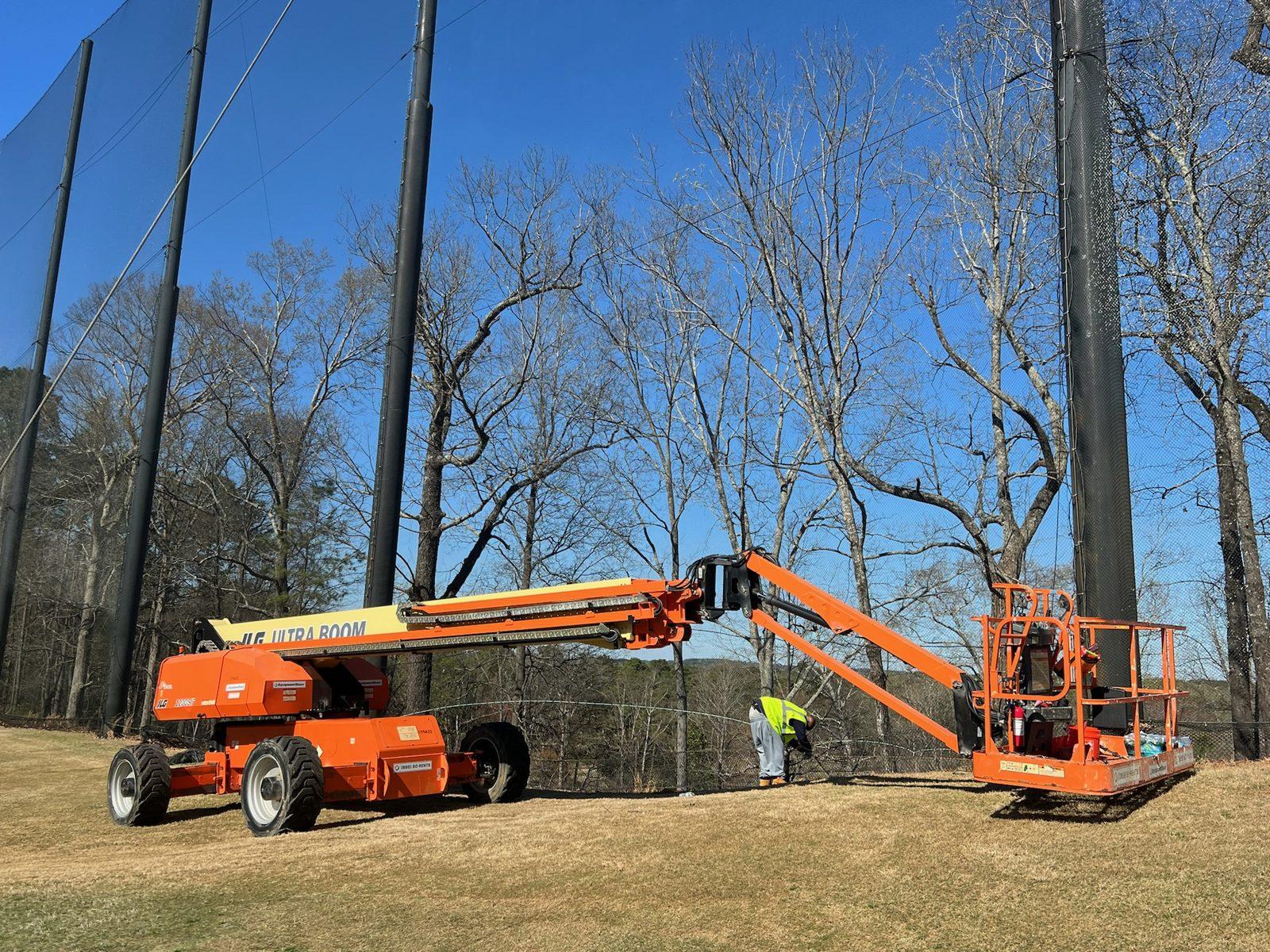 Crew working from a boom lift along the range enclosure, Full-height driving range netting enclosure at Dunwoody Country Club in Atlanta