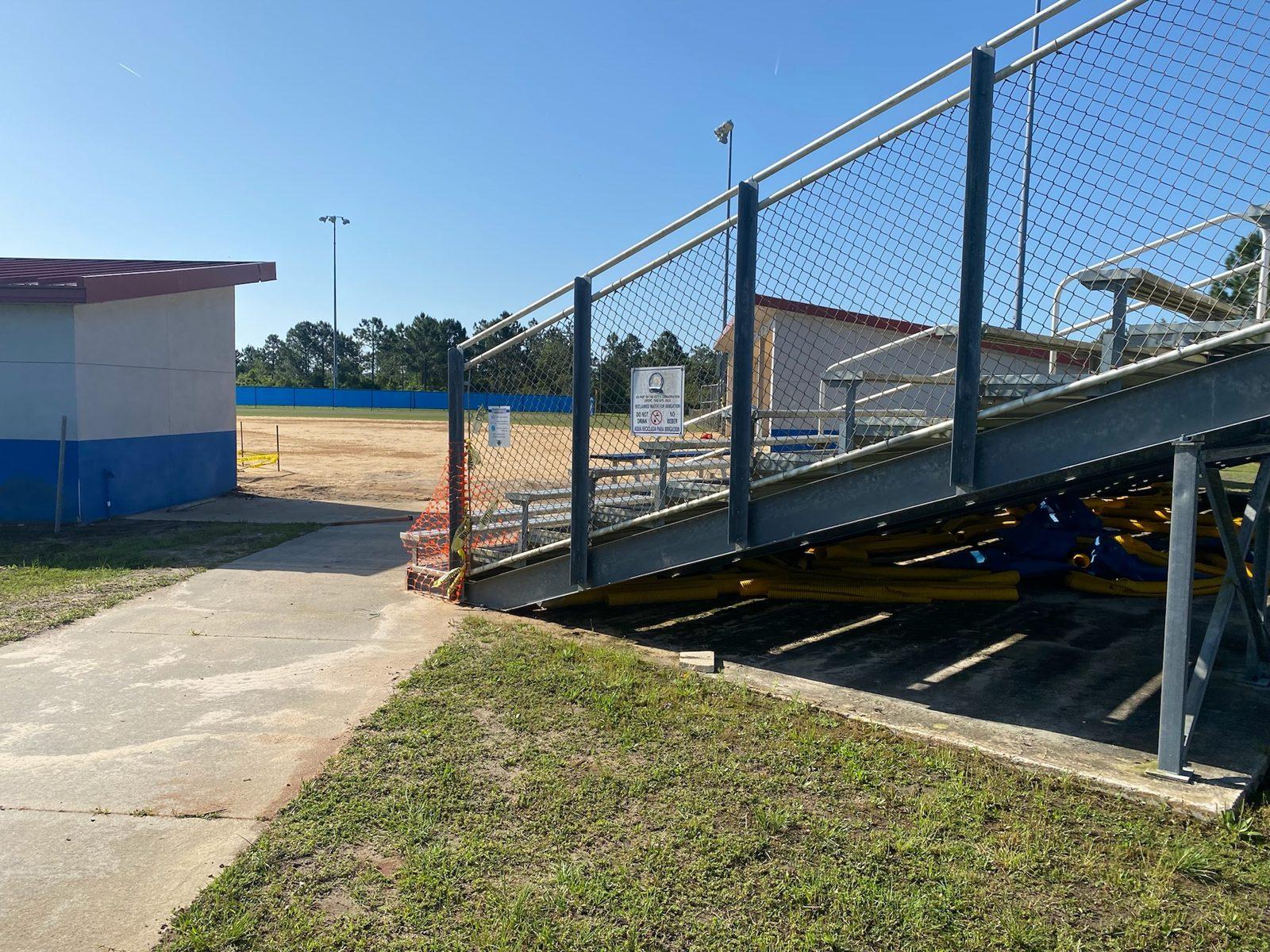 Before: Grass strip and walkway beside the bleachers before any holes were dug. Steel Pole Drilling & Setting At Matanzas High School
