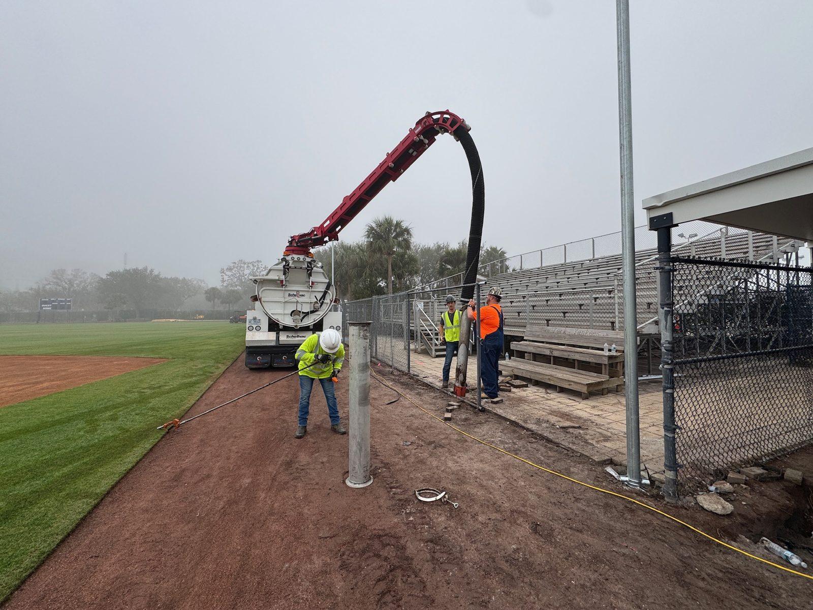 During: Vac truck clearing a hole as a new pole stands along the field. Pole Setting at George M. Steinbrenner Field in Tampa