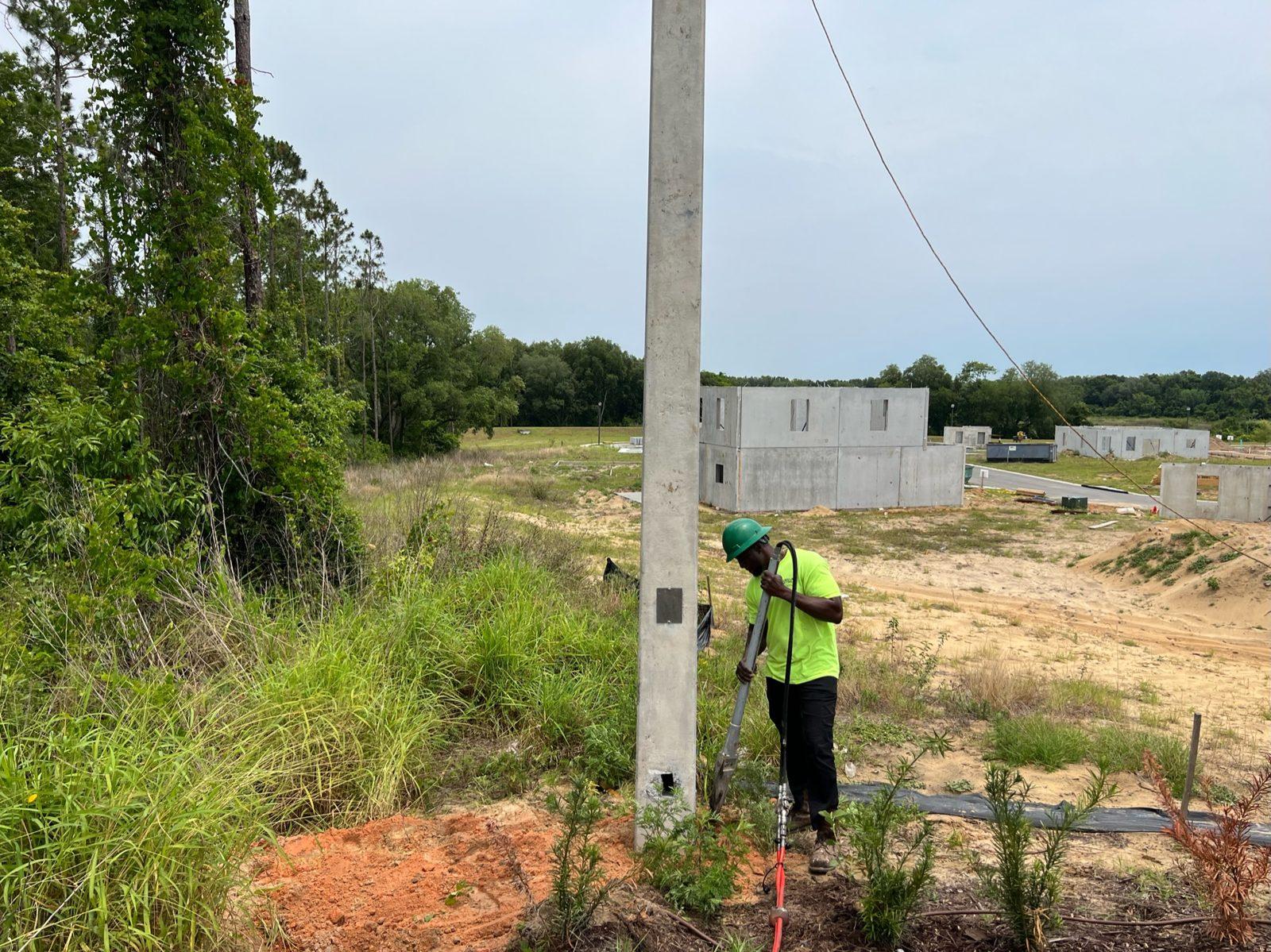 During: Crew member backfilling around a newly set concrete pole. Concrete Pole Setting at an ONX Homes Community
