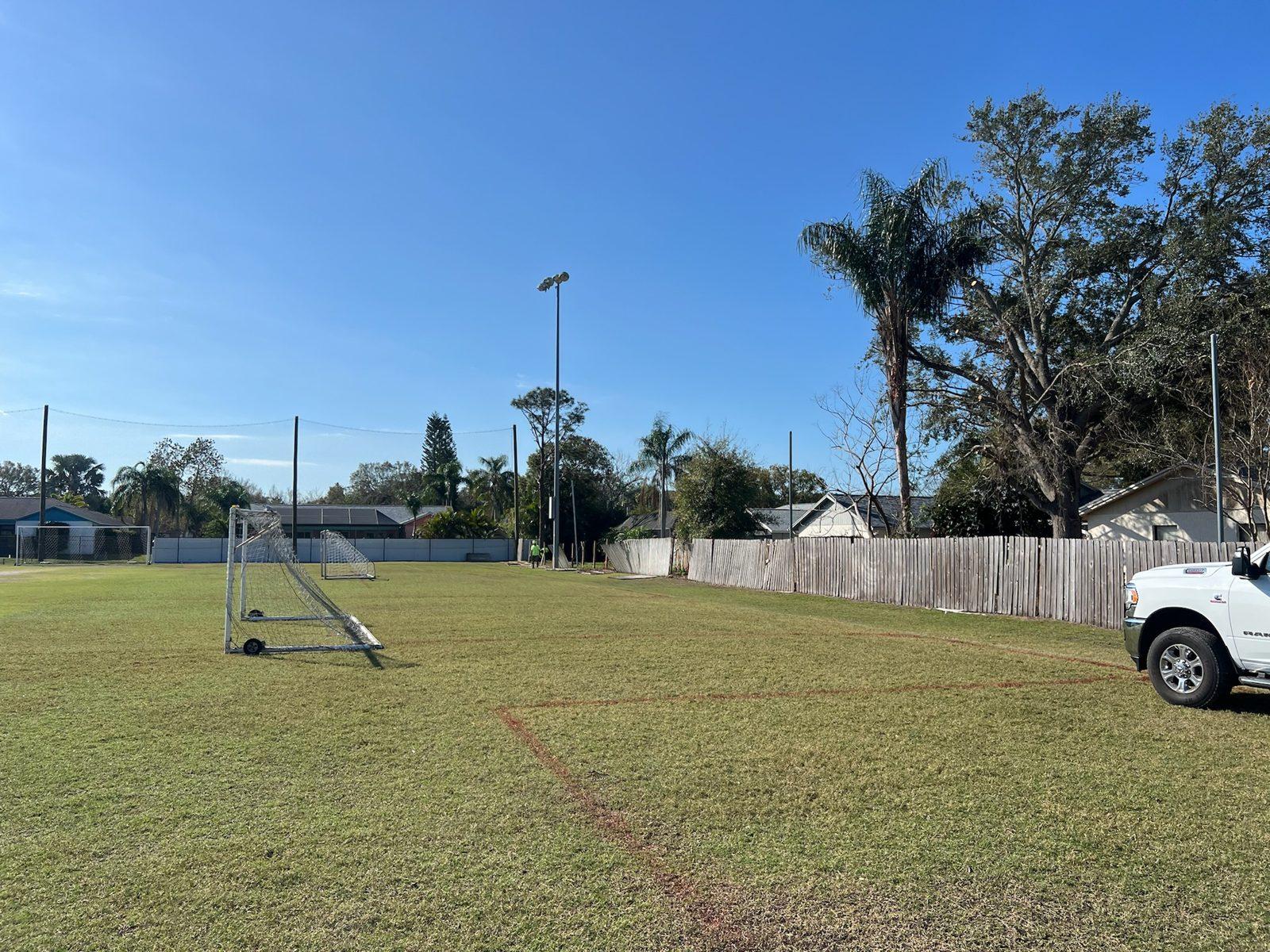 Before: Soccer field and the wood fence line along neighboring backyards before work began. Soccer and Volleyball Netting for Palm Harbor Parks & Recreation