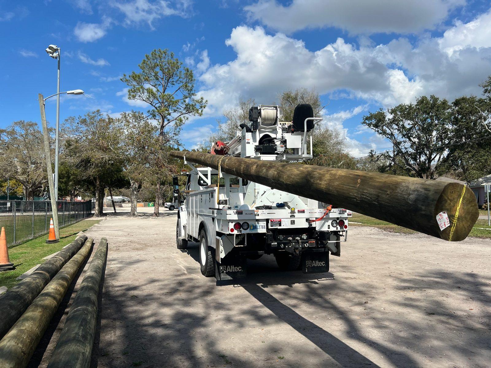 During: Bucket truck lifting a wood pole into position. Soccer and Volleyball Netting for Palm Harbor Parks & Recreation