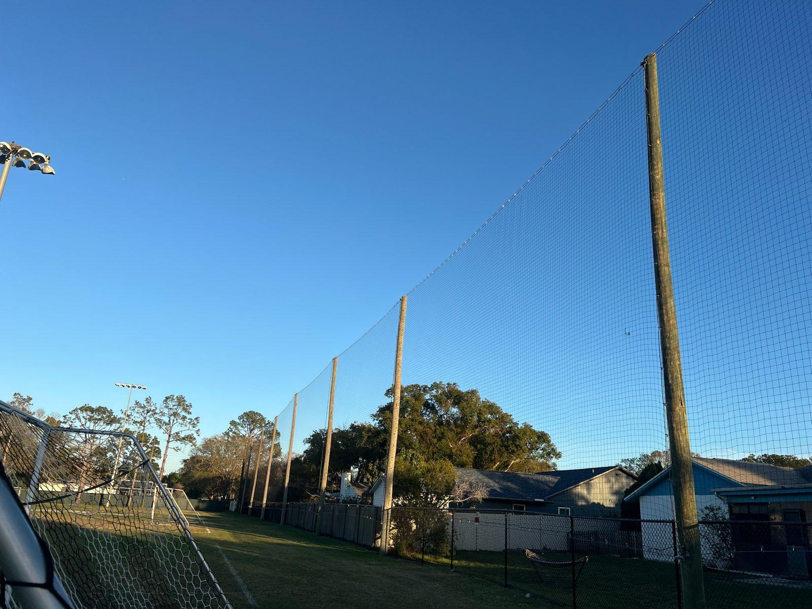 After: Finished black netting on wood poles along the soccer field and neighboring homes. Soccer and Volleyball Netting for Palm Harbor Parks & Recreation