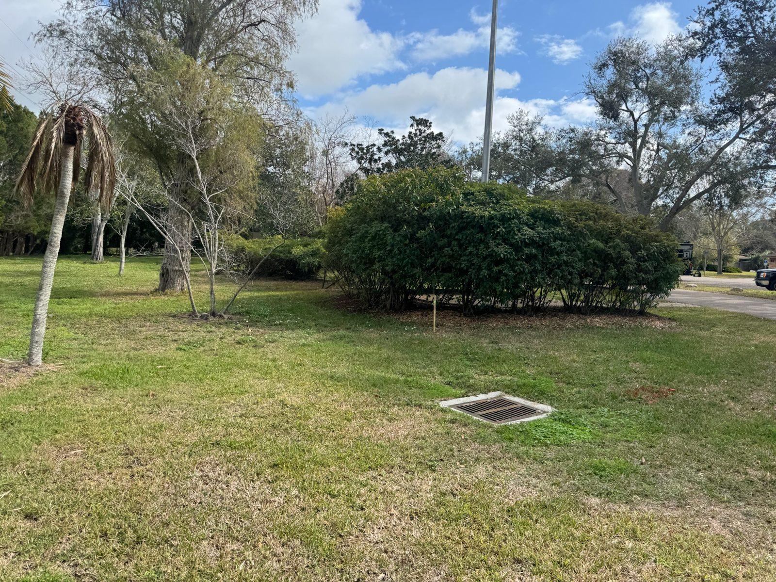Before: Open lawn at a park entrance before the pole goes in. Park Entrance Pole Setting Across Pinellas County