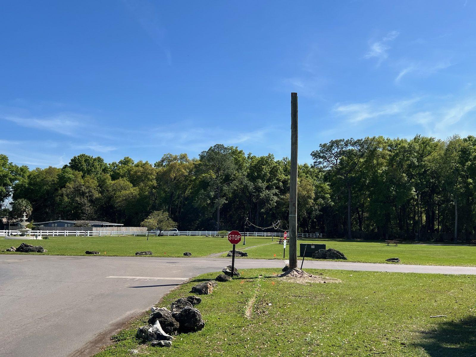 After: Pole set beside a stop sign at the edge of a large open lawn. Wood Pole Setting at an RV Park in Central Florida