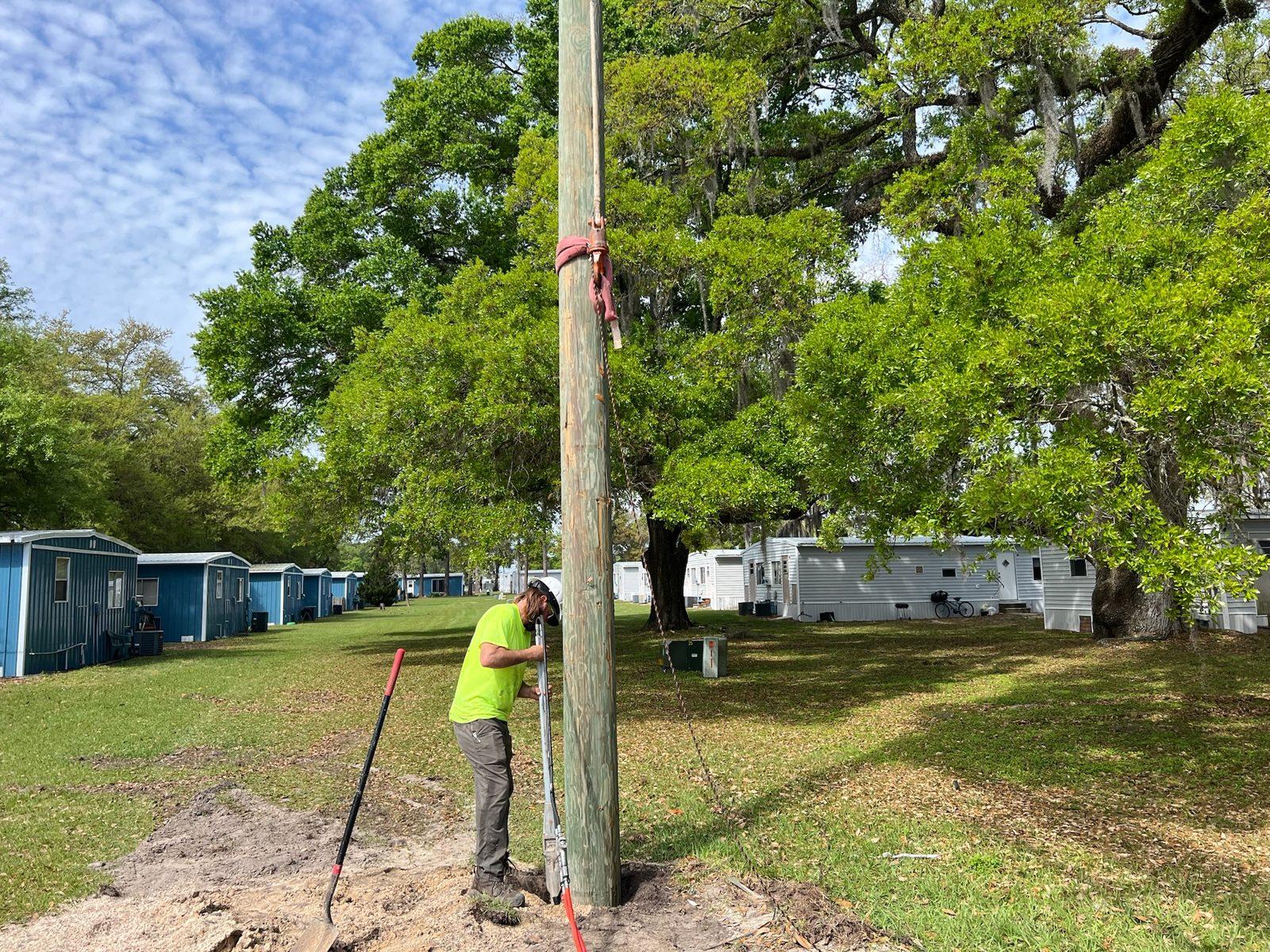 During: Crew tamps around a pole near a row of blue cottages. Wood Pole Setting at an RV Park in Central Florida