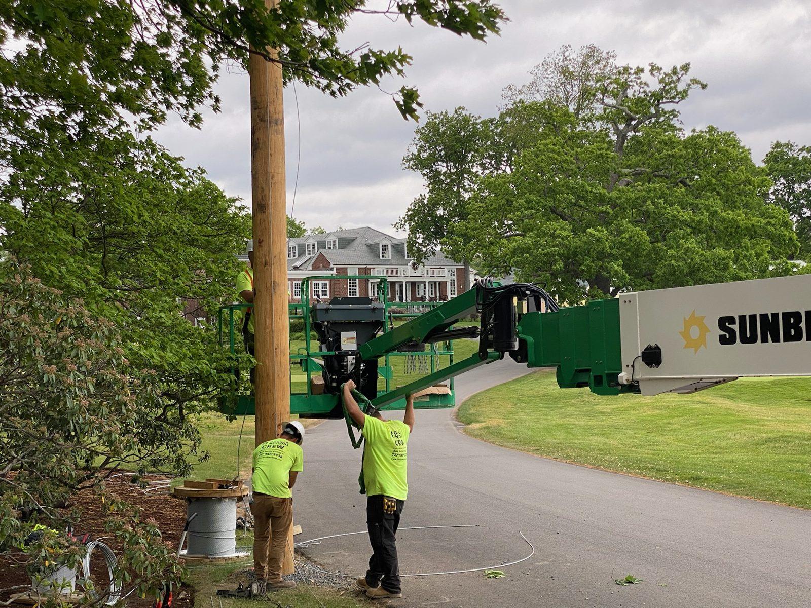During: Gorilla crew runs support cable from the lift bucket. Golf Course Netting at The Country Club, Brookline
