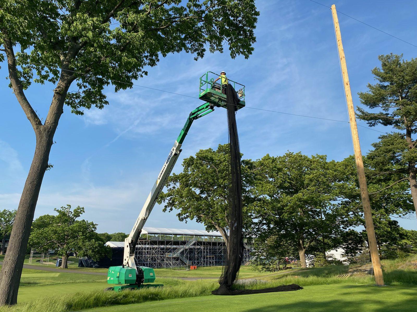 During: Lifting a bundled net panel up to the top cable. Golf Course Netting at The Country Club, Brookline