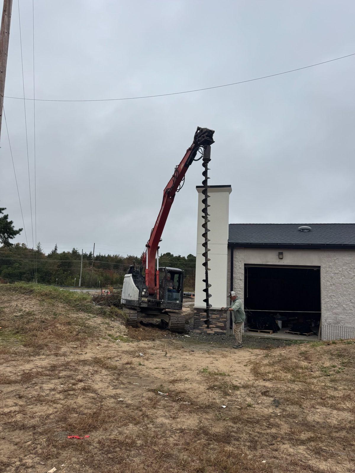 During: Auger drilling a pole hole beside the building. Driving Range Netting at Toms River Golf Center