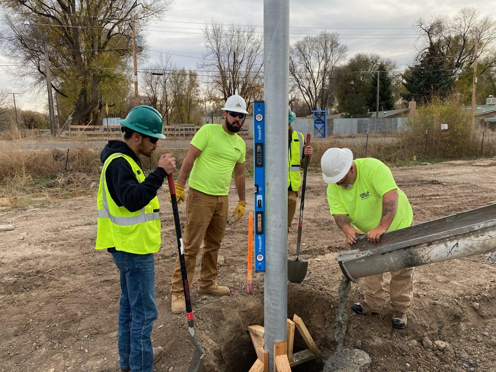 During: Crew holding a pole plumb while concrete is poured. Perimeter Netting at West Las Vegas Middle School