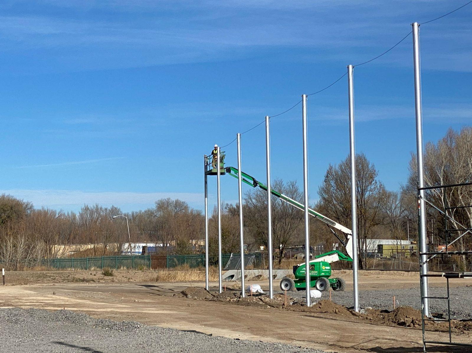 During: Top cable strung across a row of steel poles. Perimeter Netting at West Las Vegas Middle School
