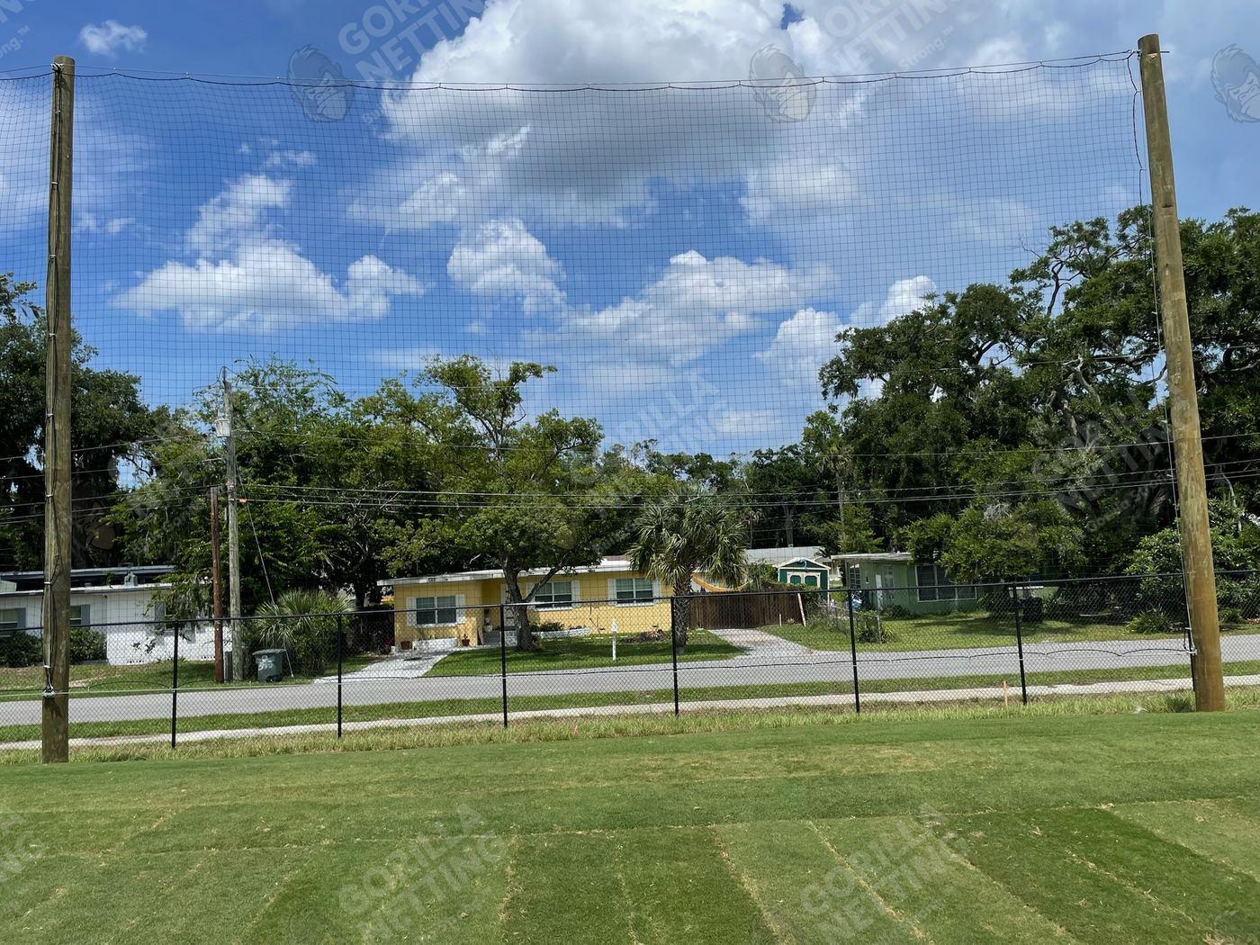 Finished outfield barrier netting on wood poles protecting homes next to the Daytona State College ballpark
