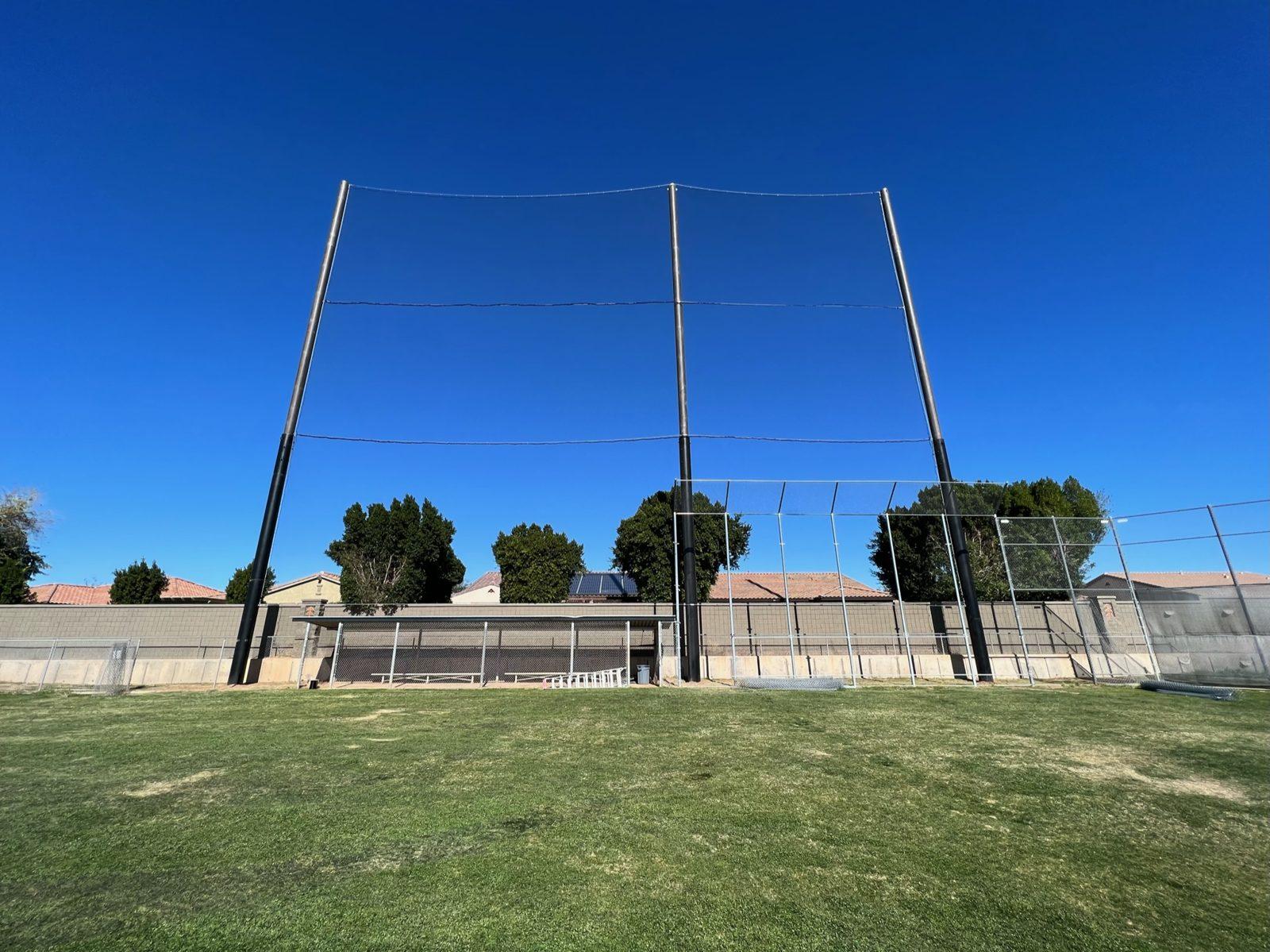 During: Hydrovac truck excavating pole holes along the fence line at sunrise. Baseball Backstop Netting at Millennium High School