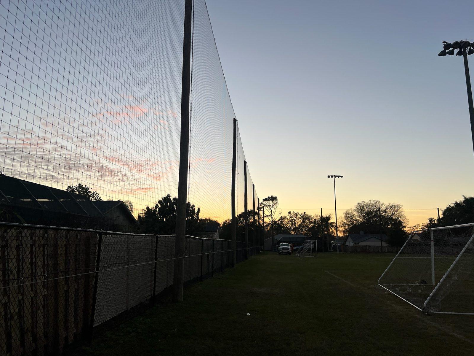 Before: Soccer field and the wood fence line along neighboring backyards before work began. Soccer and Volleyball Netting for Palm Harbor Parks & Recreation
