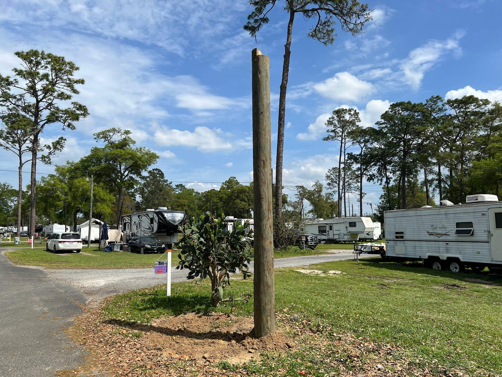 During: Boom truck lowers a wood pole into place along a vinyl fence. Wood Pole Setting at an RV Park in Central Florida